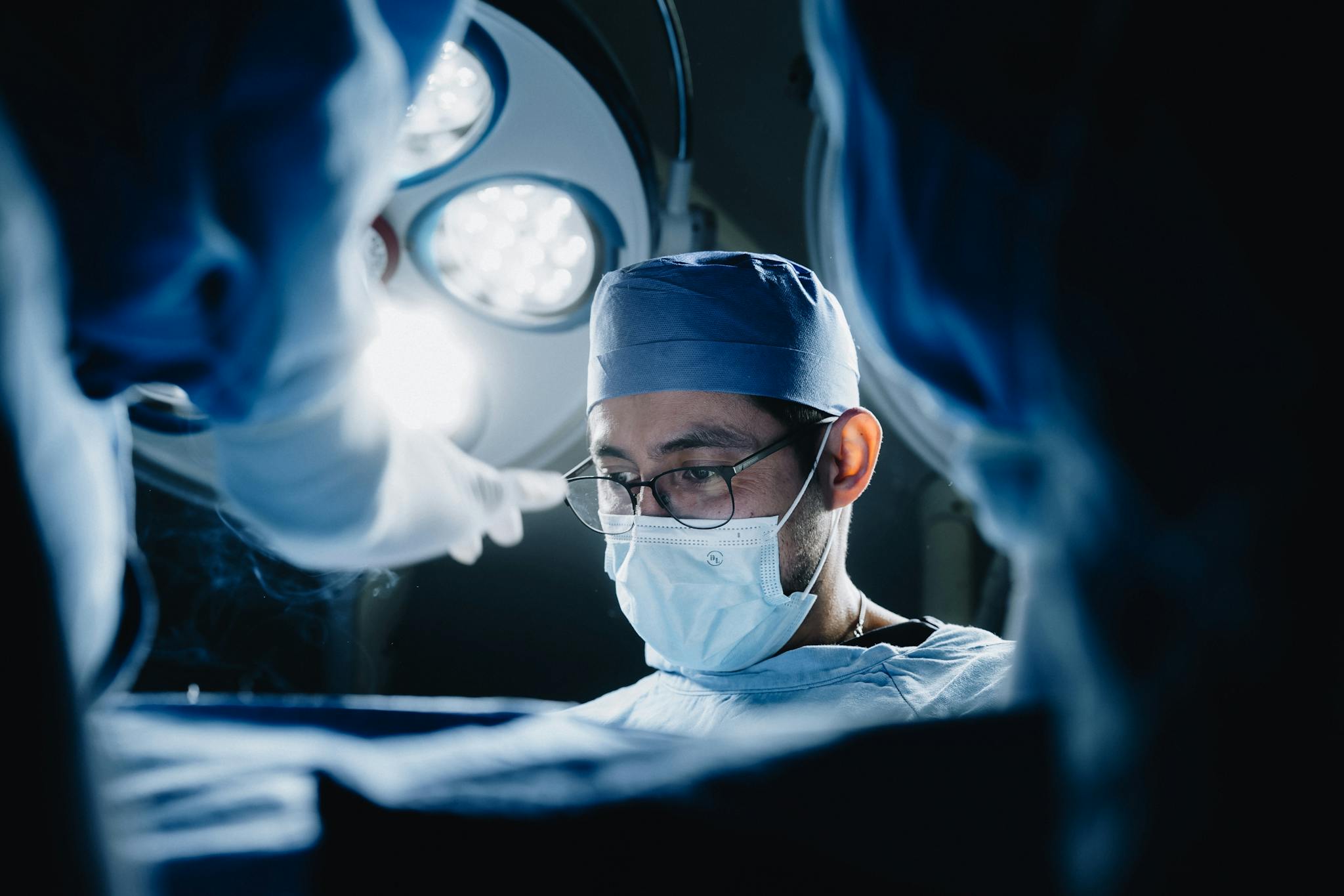 Focused surgeon in operating room with medical team in a modern hospital setting.